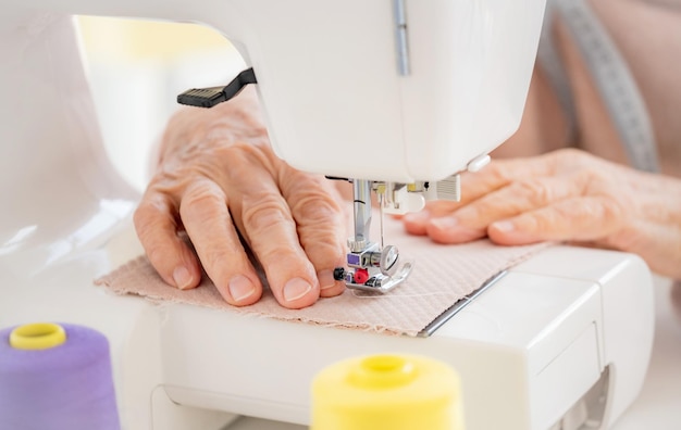 Mãos de mulher velha costurando na máquina