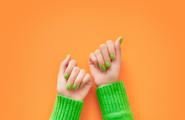 Mãos de mulheres bonitas com design de unhas primavera outono em fundo laranja Manicure pedicure conceito de salão de beleza Lugar vazio para texto