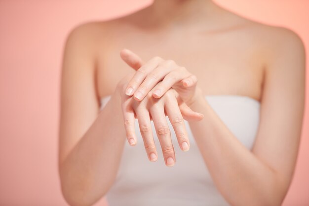 Mãos de mulheres bonitas isolando, aplicando creme, massageando