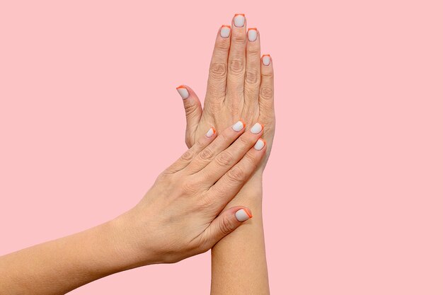 Mãos de mulheres com uma bela manicure em um fundo rosa Closeup Layout