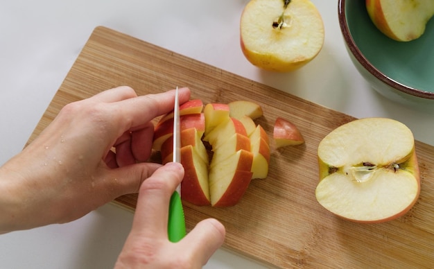 Mãos de mulheres cortam uma maçã vermelha madura Close up de Mãos Manuseando Comida