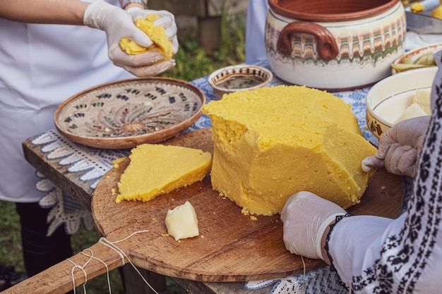 Mãos de mulheres cortando polenta na mesa com ornamentos romenos