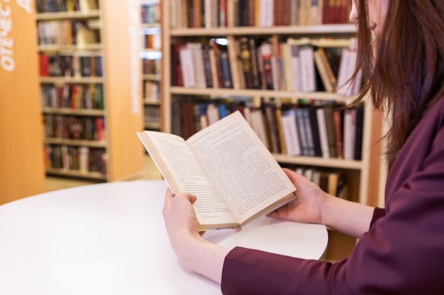 Mãos de mulheres jovens, segurando um livro. Leitura na biblioteca, foco seletivo, mãos fecham