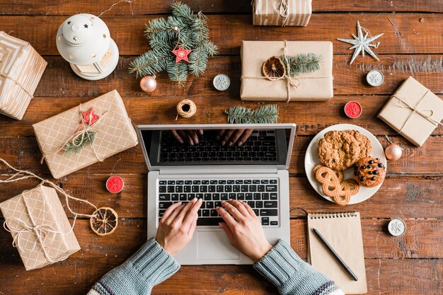 Mãos de mulheres no teclado do laptop navegando na rede em busca de lojas online para pedir presentes de Natal