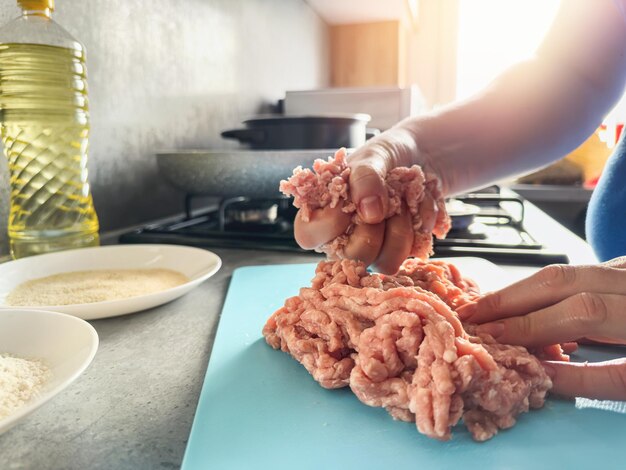 Mãos de mulheres preparando deliciosas costeletas de frango cru na cozinha doméstica