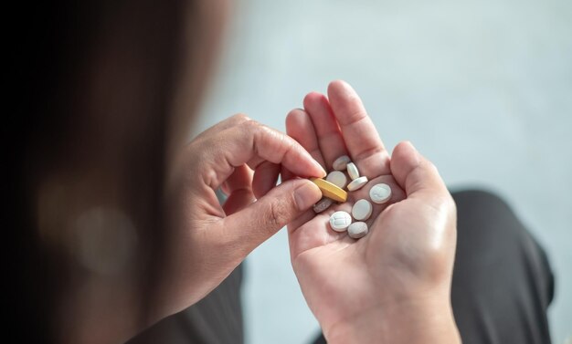 Mãos de mulheres segurando pílulas de forma e cores diferentes vista superiorCuidados de saúde e conceito médico