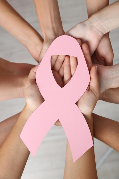 Foto mãos de mulheres unidas em círculo segurando o símbolo do câncer de mama