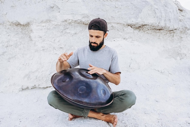 Mãos de músico tocando tambor handpan na cena da natureza