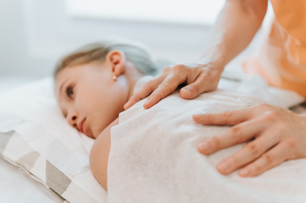 mãos de osteopata fazem terapia para meninas. sessão de tratamento de osteopatia pediátrica. Medicina alternativa