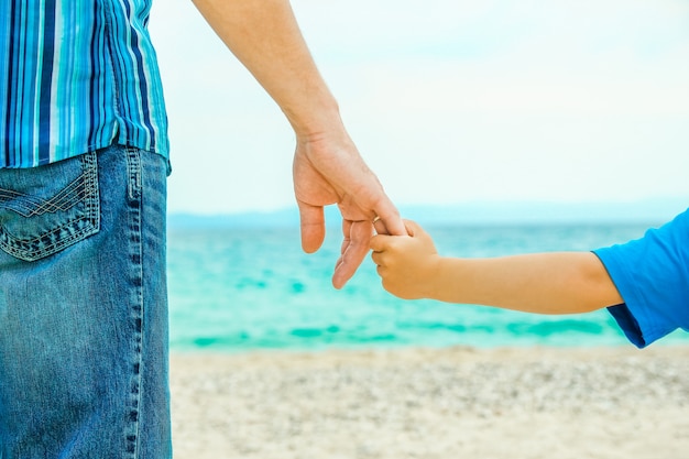 mãos de pai e filho à beira-mar