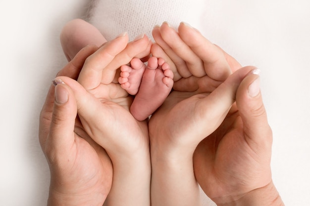 Mãos de pais. As pernas, pés do recém-nascido nas mãos da mãe e do pai. Foto de alta qualidade