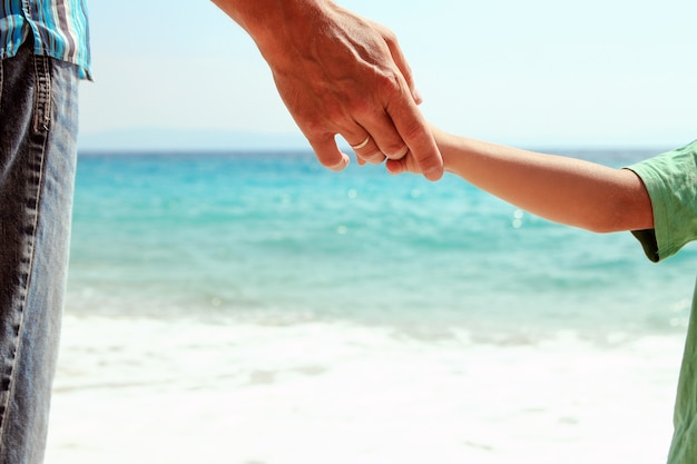 Mãos de pais e filhos à beira-mar perto da praia