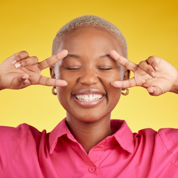 Mãos de paz e mulher negra feliz no estúdio com voto de agradecimento ou mentalidade positiva em fundo amarelo sinal V e mulher africana com boas vibrações sorriso e liberdade emoji apoio ou amor próprio