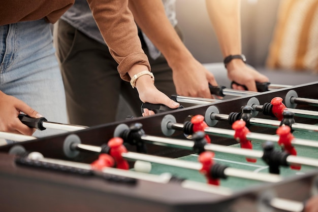 Mãos de pebolim e mesa com amigos jogando um jogo juntos dentro de casa para diversão ou recreação Diversão e lazer de futebol com um grupo de amigos juntos para jogar em uma festa ou evento de comemoração