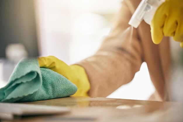 Foto mãos de pessoa e detergente na mesa com pano para bactérias de higiene ou remoção de germes em casa closeup de faxineira ou empregada limpando móveis em serviço doméstico ou desinfecção na superfície