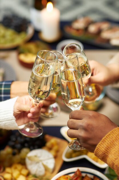 Mãos de pessoas batendo copos de champanhe celebrando o Natal em casa