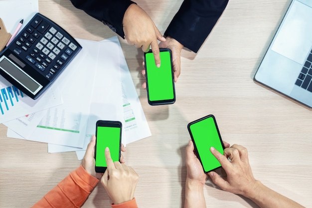 Foto mãos de pessoas de negócios usando a tela verde do telefone inteligente na vista superior.