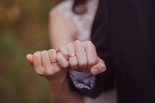 Mãos de recém-casados com anéis de casamento de ouro nos dedos, close-up