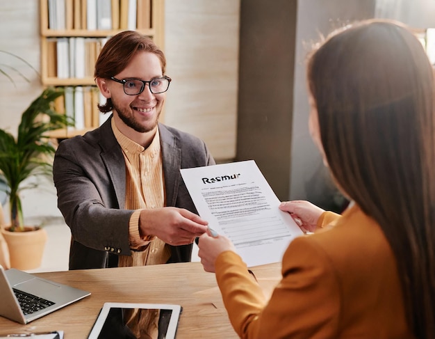 Mãos de recrutador segurando currículo na frente do candidato na mesa