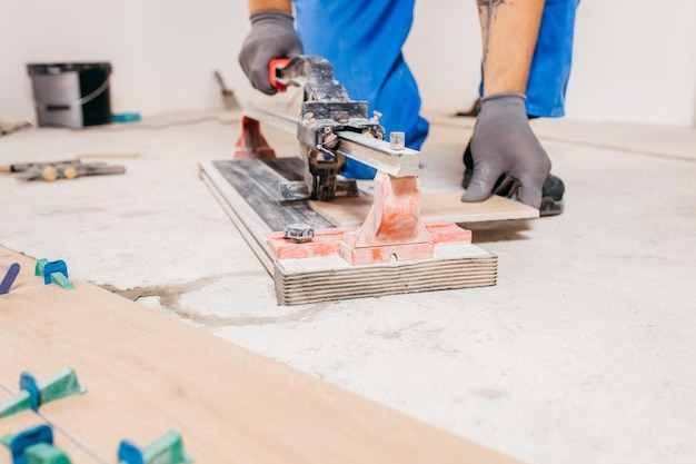 Mãos de reparador cortar telhas cerâmicas no cortador de telhas no chão. fechar-se