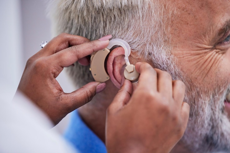 Foto mãos de saúde e médico com aparelho auditivo para homem para suporte de comunicação closeup médico e uma enfermeira com implante para um paciente com deficiência para ajuda na escuta e conversa