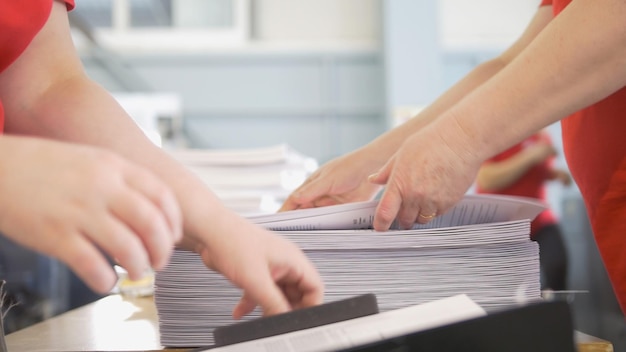 Mãos de trabalhadoras mudam as pilhas de papel