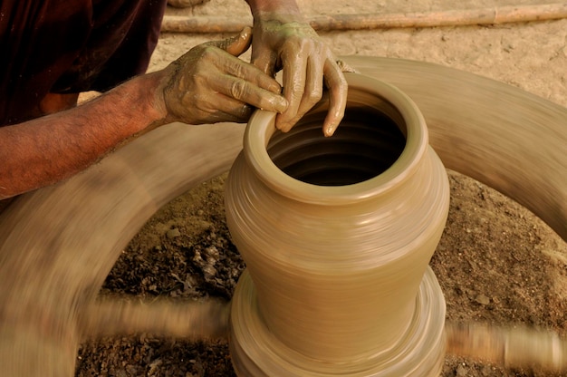 Mãos de um artesão indiano fazendo potes de barro