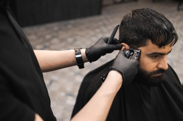 Mãos de um barbeiro cortando um homem com um aparador cabeleireiro fazendo um corte de cabelo para um cliente