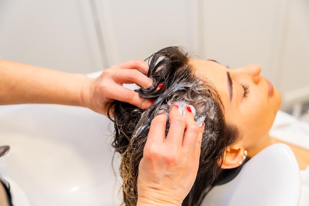Mãos de um cabeleireiro lavando o cabelo danificado de uma mulher