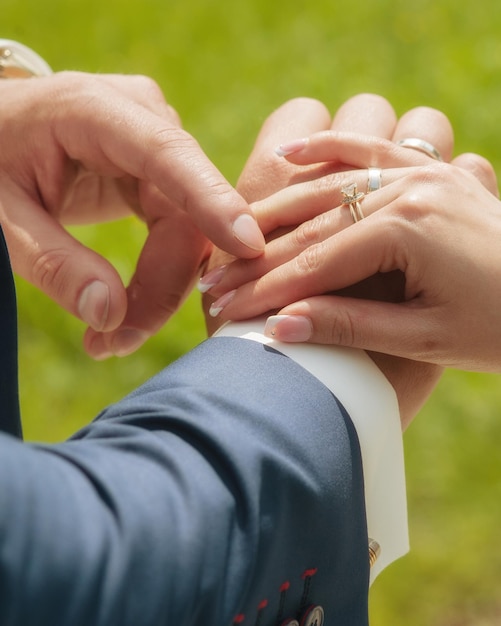 Mãos de um casal apaixonado coloca anéis de casamento menino e menina de mãos dadas casal