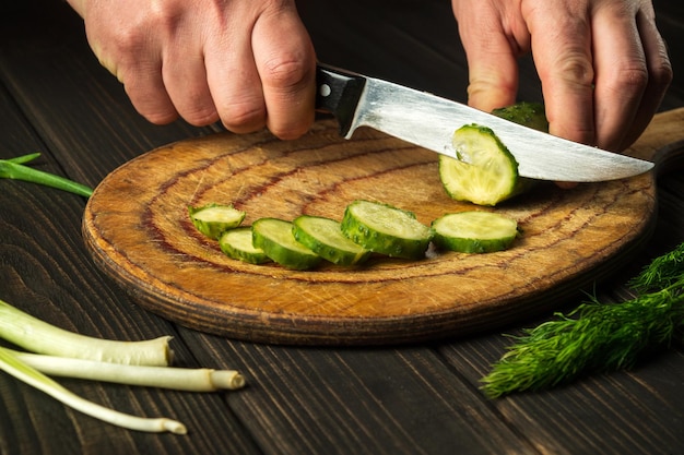 Mãos de um chef com uma faca enquanto cozinha na cozinha