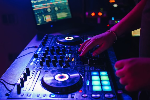 Mãos de um dj em uma cabine tocando no mixer