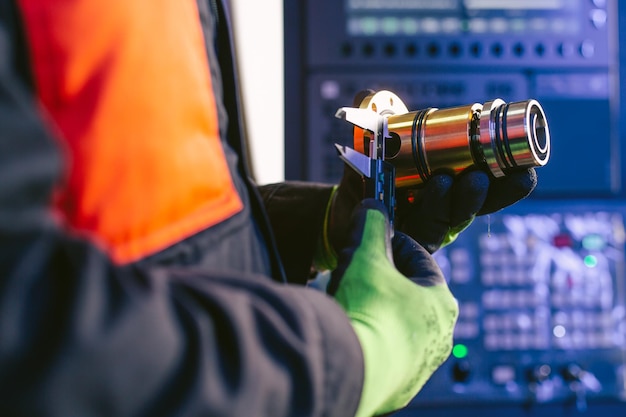 Mãos de um engenheiro medem uma peça de metal com um paquímetro digital Controle de qualidade da peça usinada em um torno