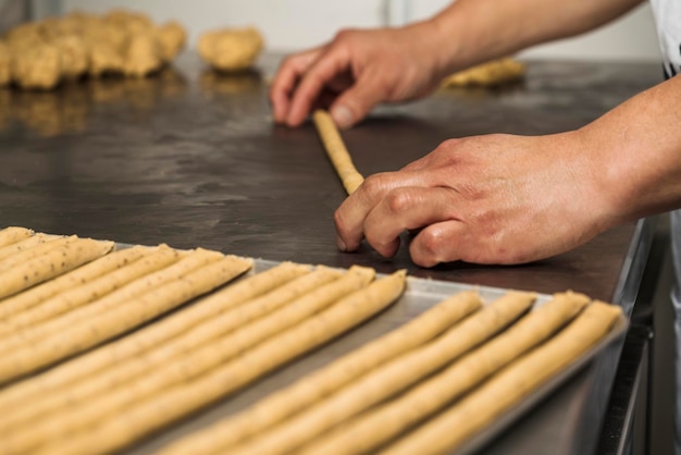 Mãos de um homem fazendo rolos de pão artesanal em uma padaria