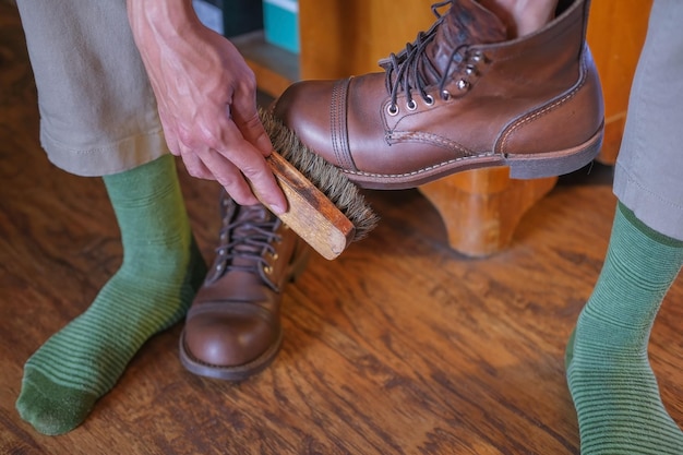 Mãos de um homem limpando um sapato estiloso de couro com uma escova de sapato close-up em casa, cuidados com os sapatos