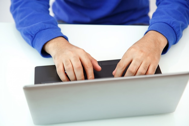 Foto mãos de um jovem digitando em um laptop. a vista do topo