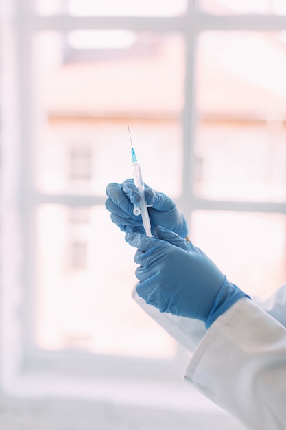 Mãos de um médico segurando uma seringa