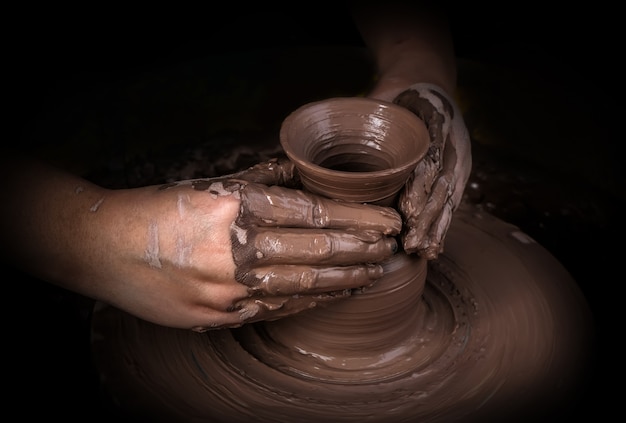 Mãos de um oleiro, criando um pote de barro no círculo