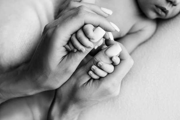 Mãos de um recém-nascido dormindo nas mãos da mãe closeup dedos minúsculos de um recém-nascido segurando os polegares da mão da mãe39s fotografia macro de estúdio conceitos de família e amor preto branco