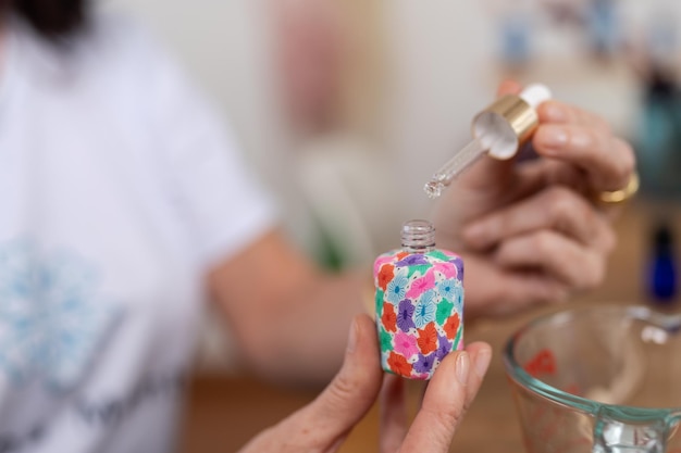 Mãos de um terapeuta preparando uma fragrância para um tratamento de aromaterapia