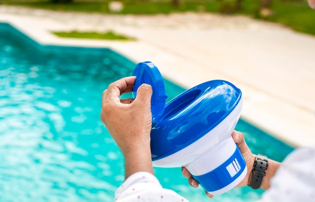 Mãos de um trabalhador instalando um flutuador de cloro de piscina uma pessoa segurando um dispensador de cloro de piscina Mãos segurando um dispensador de cloro de piscina Mão de um trabalhador de desinfecção de piscina segurando um dispensador de cloro