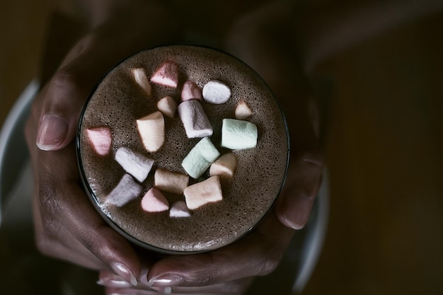 Foto mãos de uma garota africana segurando cacau com um marshmallow