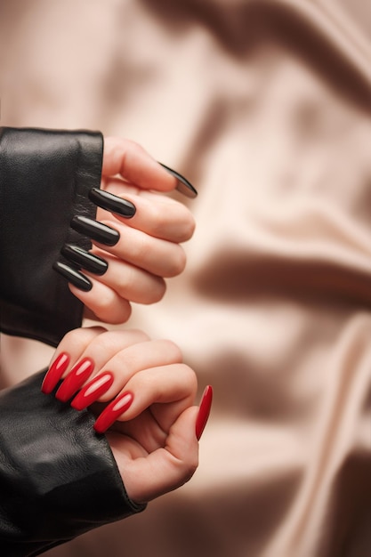 Foto mãos de uma jovem com manicure preto e vermelho nas unhas