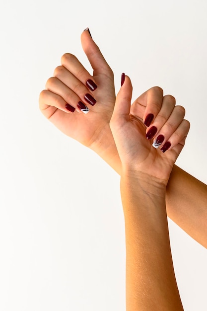 Mãos de uma jovem mostrando fundo branco de unhas pintadas