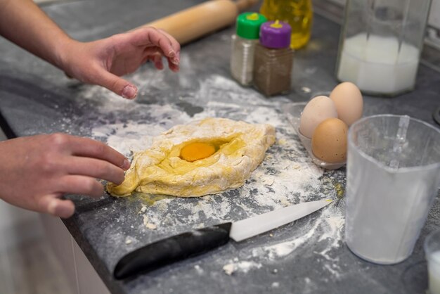 Mãos de uma jovem preparando massa para bolinhos com batatas O conceito de cozinhar por uma mulher