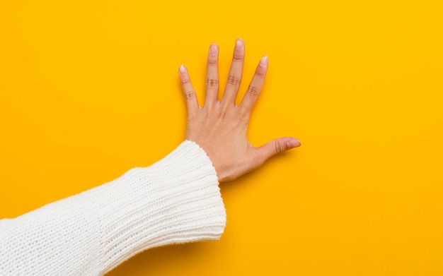 Mãos de uma linda mulher com unhas compridas limpas em um fundo amarelo