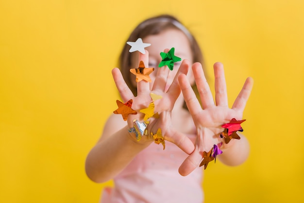Mãos de uma menina com confetes coloridos nas mãos