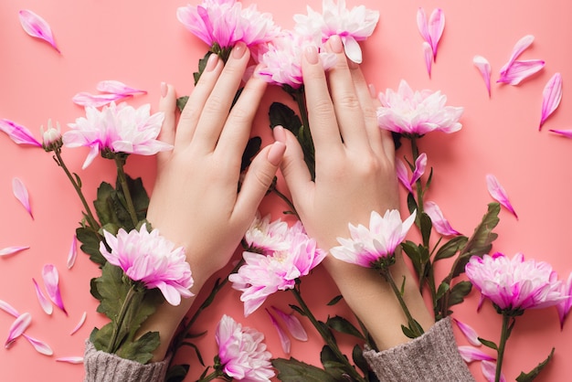 Mãos de uma menina com uma manicure suave em flores
