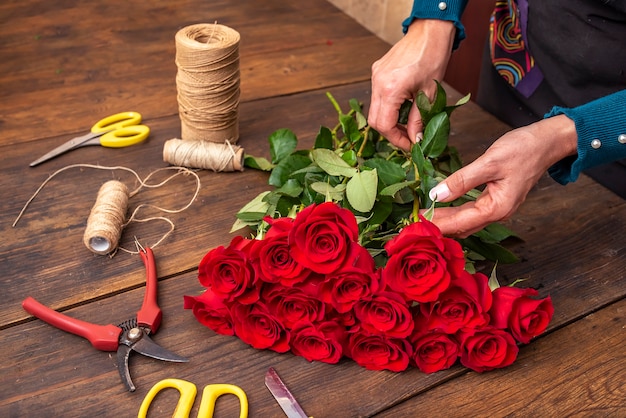 Mãos de uma mulher arrumando um buquê de flores em uma mesa