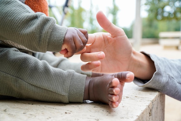 Mãos de uma mulher caucasiana e um bebê africano negro multirracial